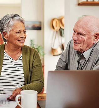 Photo of three people smiling and chatting with a laptop