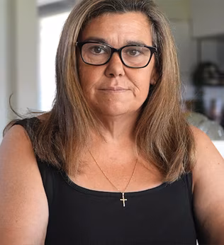Photo of woman in black top and glasses wearing a crucifix