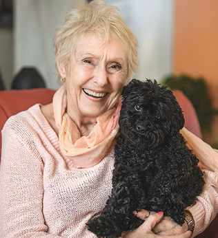 Photo of a woman in apricot with an adorable black puppy
