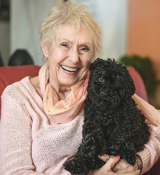 Photo of a woman in apricot with an adorable black puppy