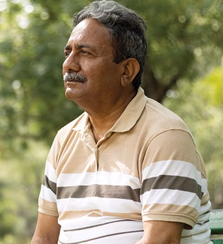 Photo of a man in a striped polo sitting on a park bench