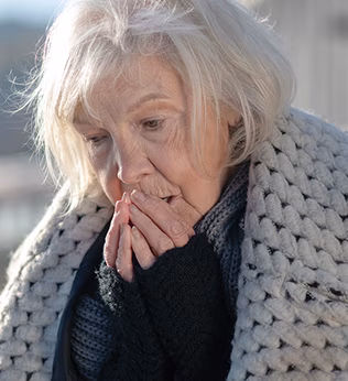 Photo of a woman wearing a warm coat and blowing on her fingers
