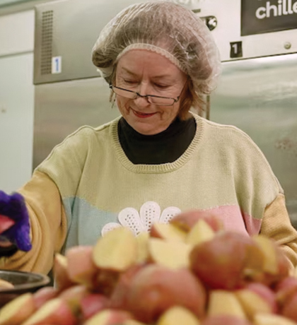 Photo of a woman prepping potatoes in a commercial kitchen