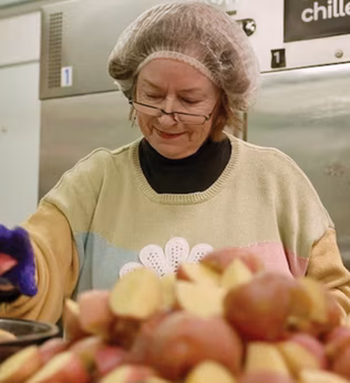 Photo of a woman prepping potatoes in a commercial kitchen