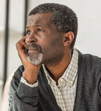 Photo of a man looking pensive with his chin resting on his palm