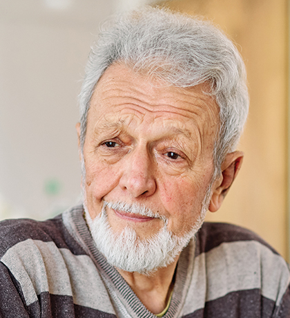 Photo of a bearded man wearing a brown and grey striped t-shirt