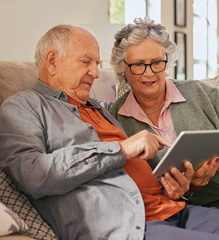 Photo of a couple sitting on a couch with a tablet