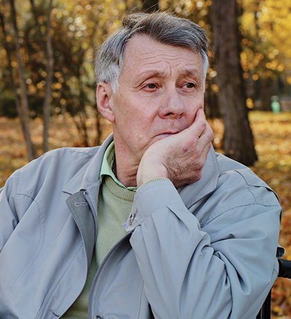 Photo of seated man with golden autumn leaves behind him