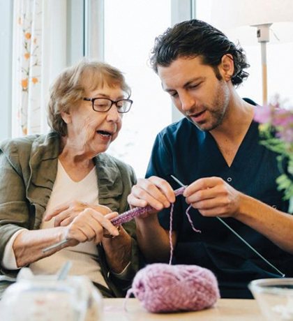 Photo of a woman showing a man how to knit