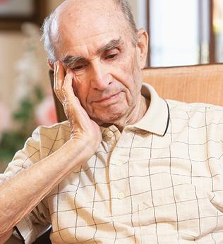 Photo of man in a tan chair resting his head on his hand
