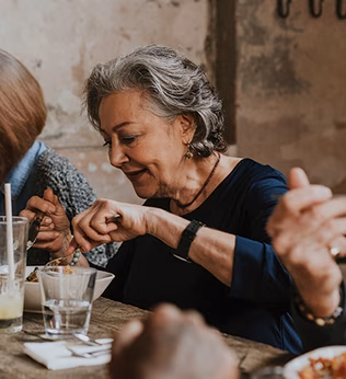 Photo of people eating together in rustic surrounds