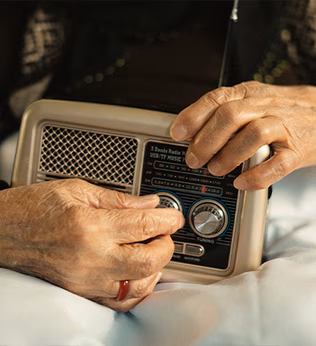 Photo of hands turning the knobs of a traditional radio