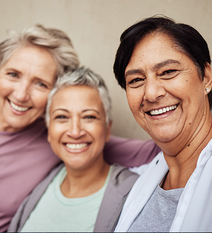 Photo of three women wearing muted pinks and greys
