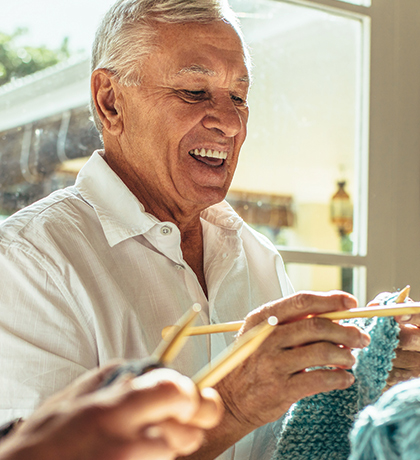 Photo of men laughing as they knit together
