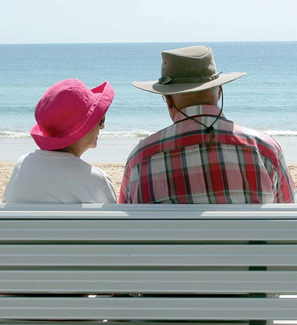 Photo of a couple sitting on a bench at the seaside