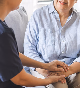 Photo of a helper holding the hands of a woman in a pale blue shirt