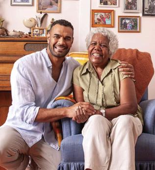 Photo of a young man embracing an older lady in a blue armchair