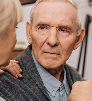 Photo of a woman with a blonde ponytail and her hand on a man's shoulder
