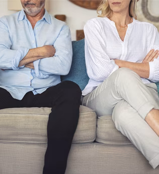 Photo of two people with crossed arms sitting on a sofa