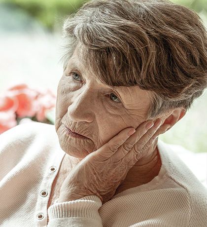 Photo of a woman with a walking stick sitting in front of flowers
