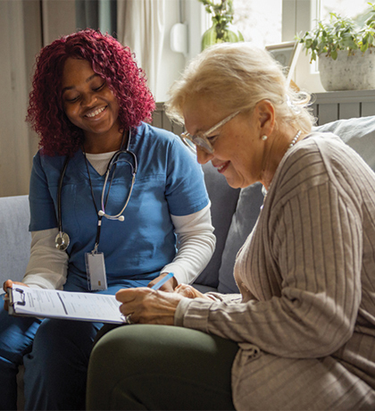 Photo of a health worker sitting with a woman filling out a form