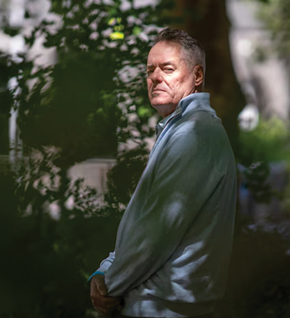 Photo of a man standing in dappled light in a garden