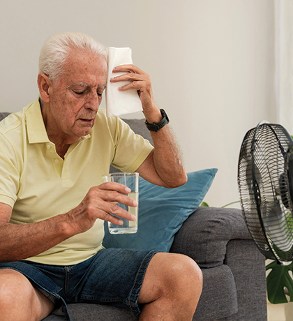 Photo of a man sitting in front of a fan with a glass of water