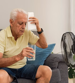 Photo of a man sitting in front of a fan with a glass of water