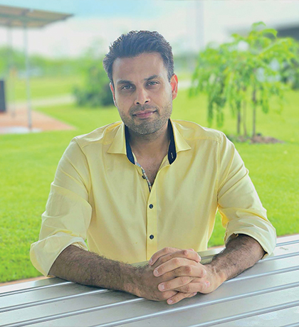 Photo of a man in a yellow shirt sitting at an outdoor table