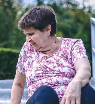 Photo of a woman in a floral pink t-shirt sitting outside