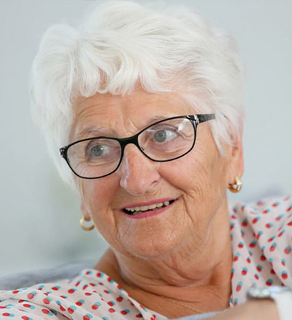 Photo of a white haired woman wearing black framed glasses