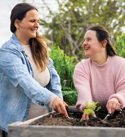 Photo of two laughing women planting in a community garden