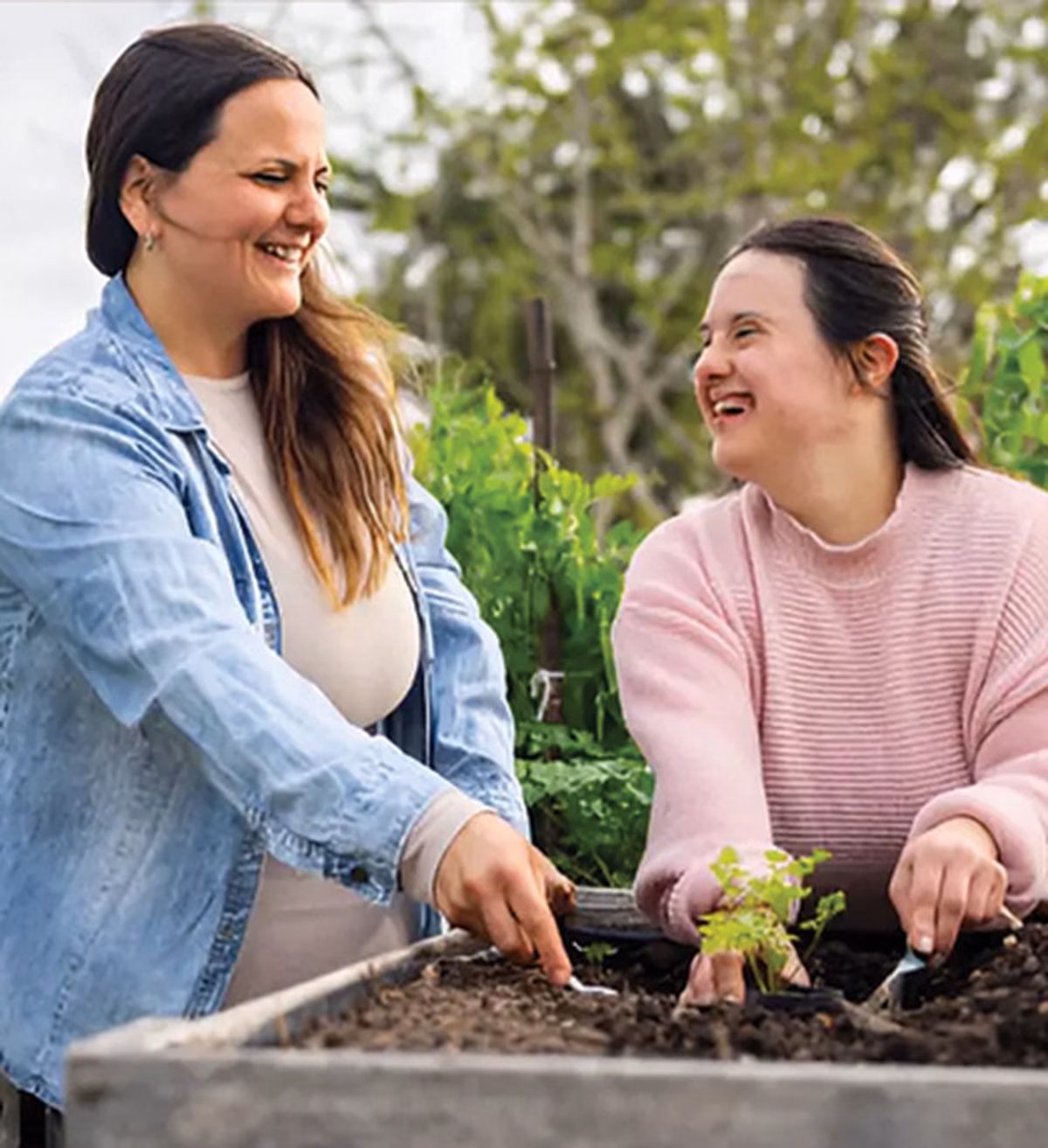 Photo of two laughing women planting in a community garden