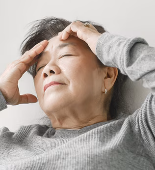 Photo of woman in grey sweatshirt massaging her forehead