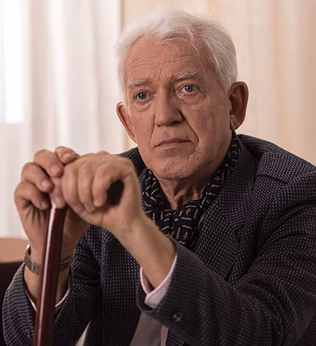 Photo of a man resting his hands on his walking stick
