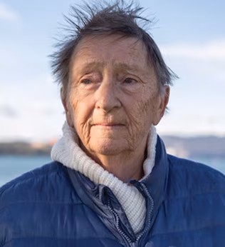 Photo of a woman by the beach wearing a blue parka