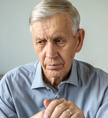 Photo of a seated man resting his hands on a walking stick