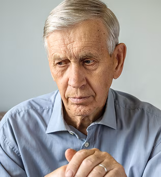 Photo of a seated man resting his hands on a walking stick