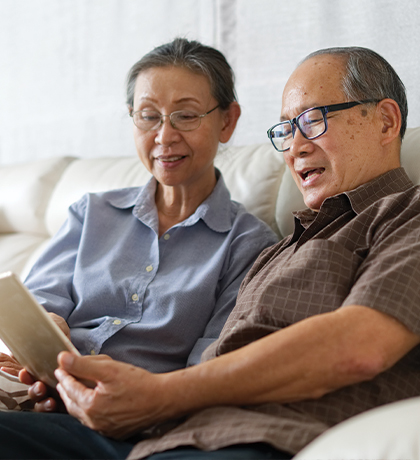Image of two older Asian Australians reading on a tablet