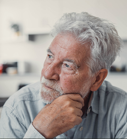Photo of a man with silver hair and beard resting his chin on his hand