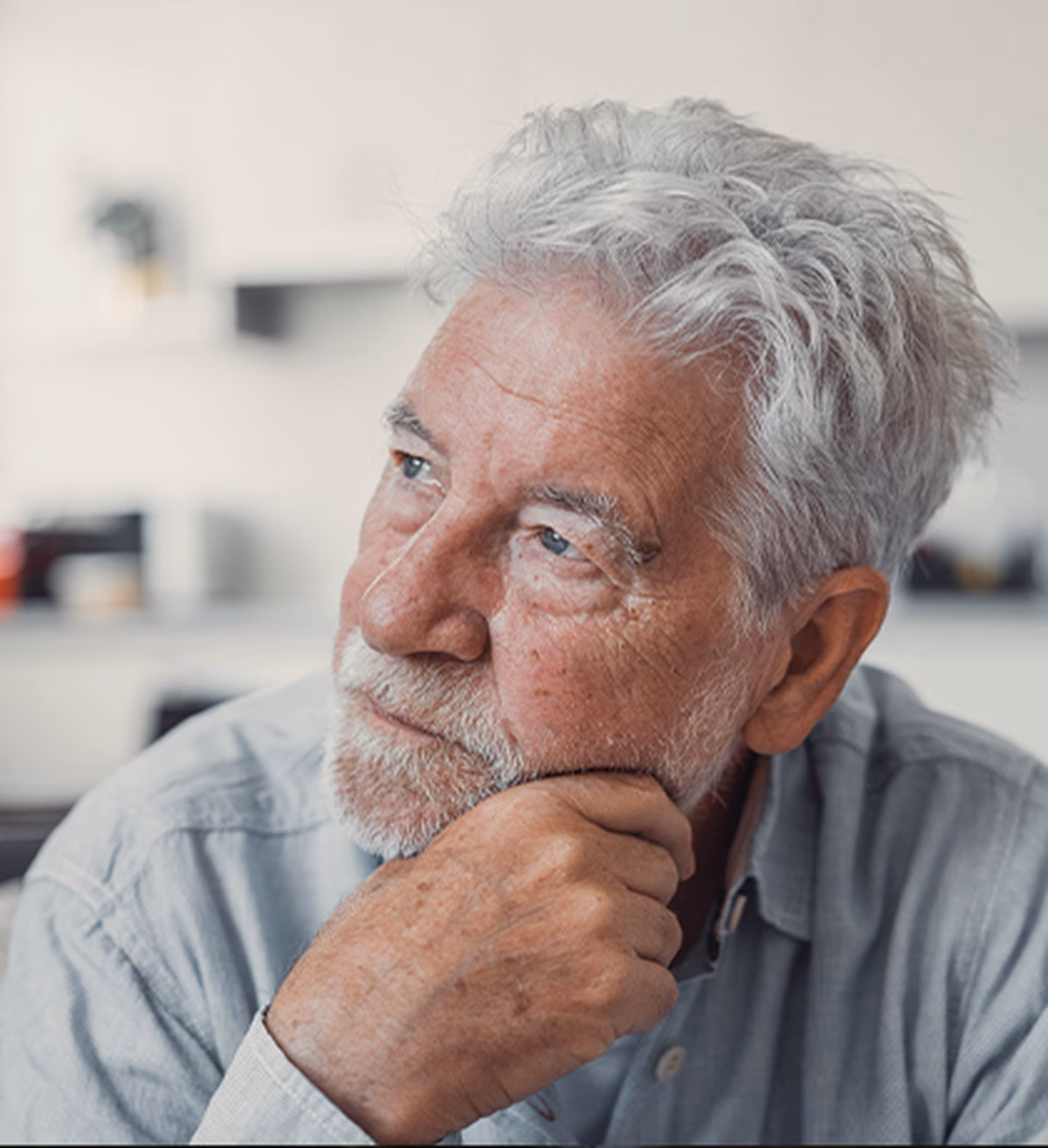 Photo of a man with silver hair and beard resting his chin on his hand