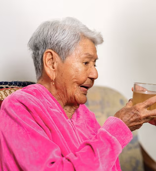 Photo of a woman giving a senior lady something to drink