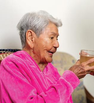 Photo of a woman giving a senior lady something to drink