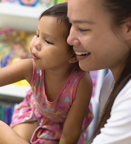 Photo of a young child and woman pointing to an open book