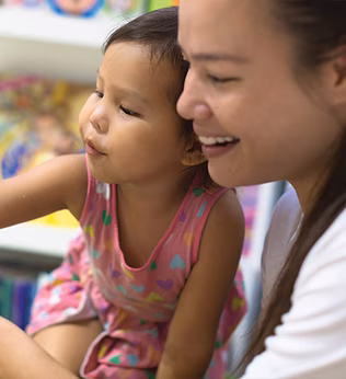 Photo of a young child and woman pointing to an open book