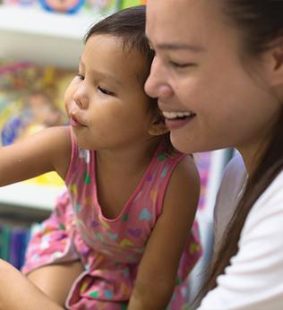 Photo of a young child and woman pointing to an open book