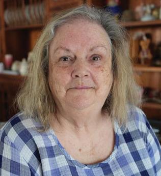 Photo of a woman wearing a blue checked dress in a room full of knick knacks