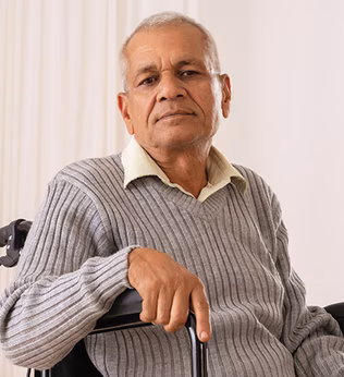 Photo of a man  with a grey jumper sitting in a wheelchair