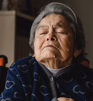 Photo of an elderly woman asleep in her wheelcahiar