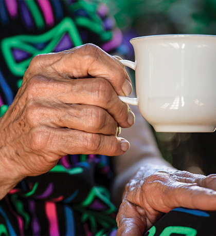 Photo of a senior hand holding a white tea cup